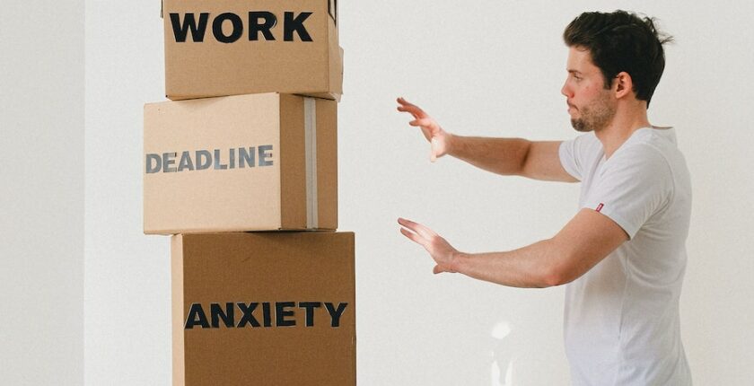 Man managing boxes with words work, deadline, and anxiety.