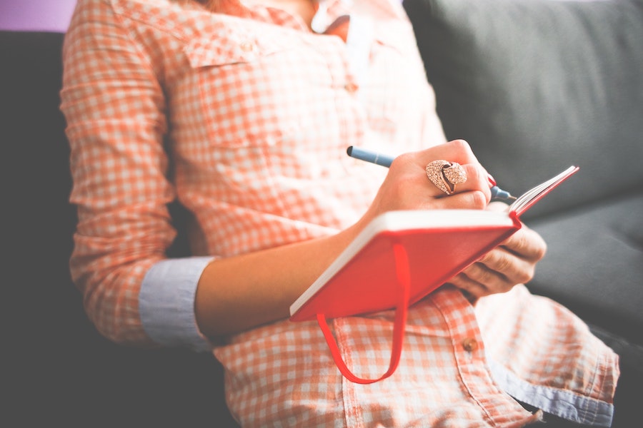 Woman journaling on a couch.