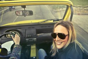 Woman smiling in yellow car.