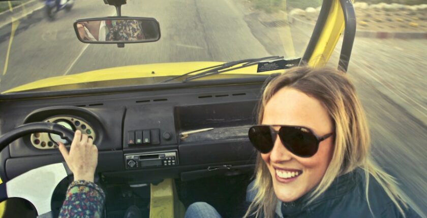 Woman smiling in yellow car.