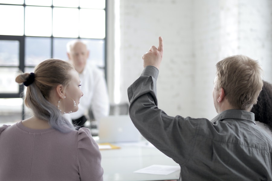 Worker raising their hand in a meeting.