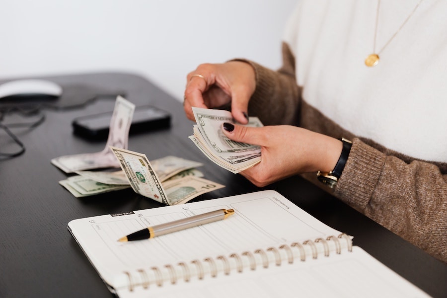 Woman at desk counting money.