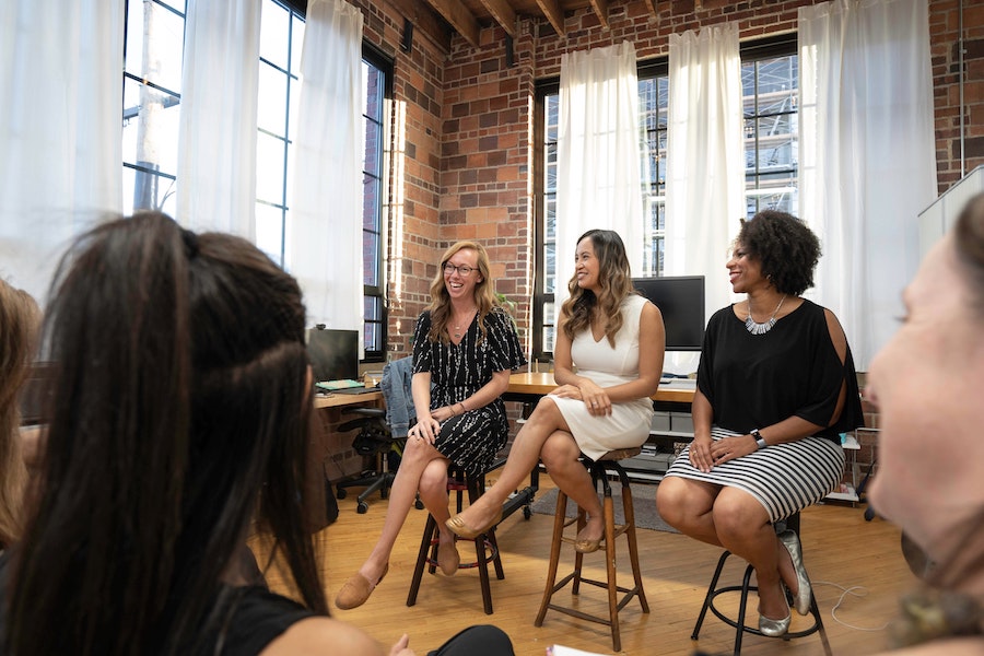 Three women leading a discussion in an office.