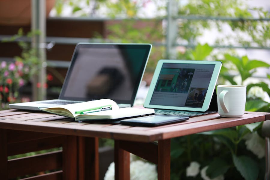 A desk with a computer, tablet, and notebook.