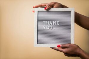 Hands holding a sign that says thank you.