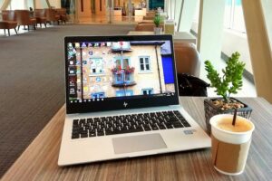 Laptop and a cup of coffee on well-lit table.