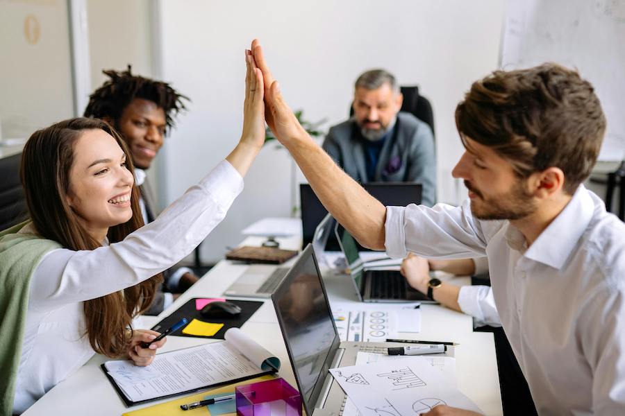 Two team members giving one another a high five at a work meeting.