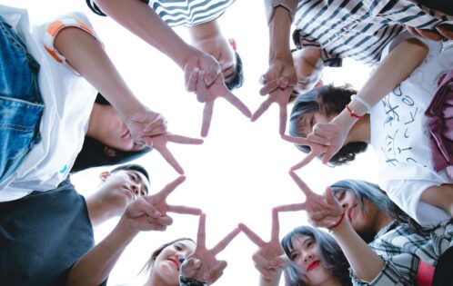 Group of people working together to make a star shape with their hands.