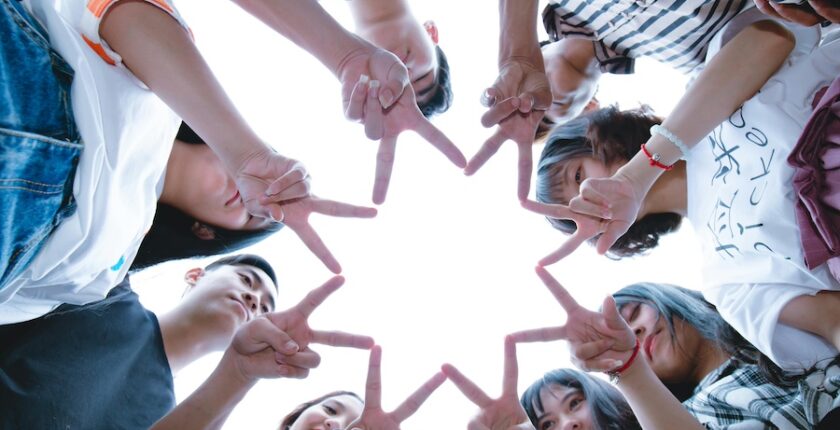 Group of people working together to make a star shape with their hands.