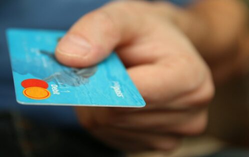 A man's hand holding out a debit or credit card.