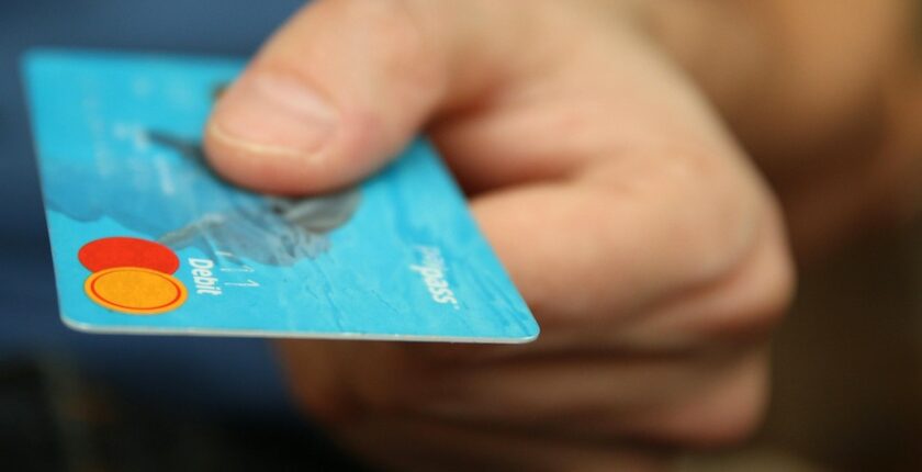 A man's hand holding out a debit or credit card.