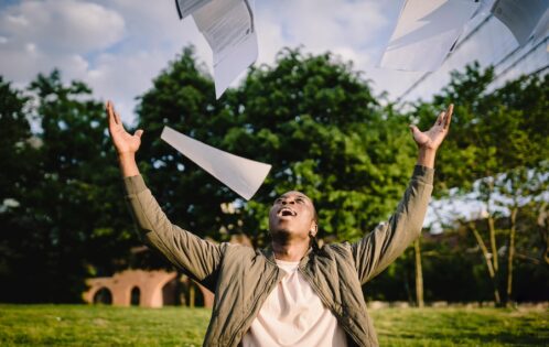 Man throwing papers into the air and smiling.