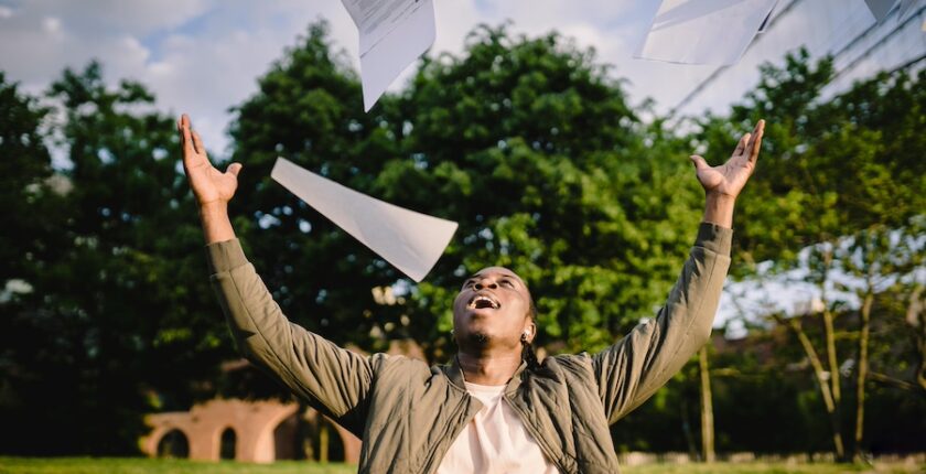 Man throwing papers into the air and smiling.