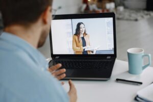 One employee watching another give a presentation on a laptop.