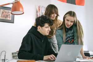 A group of young workers looking at a laptop together.