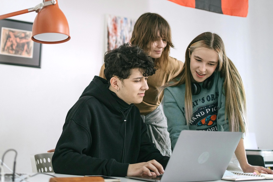 A group of young workers looking at a laptop together.