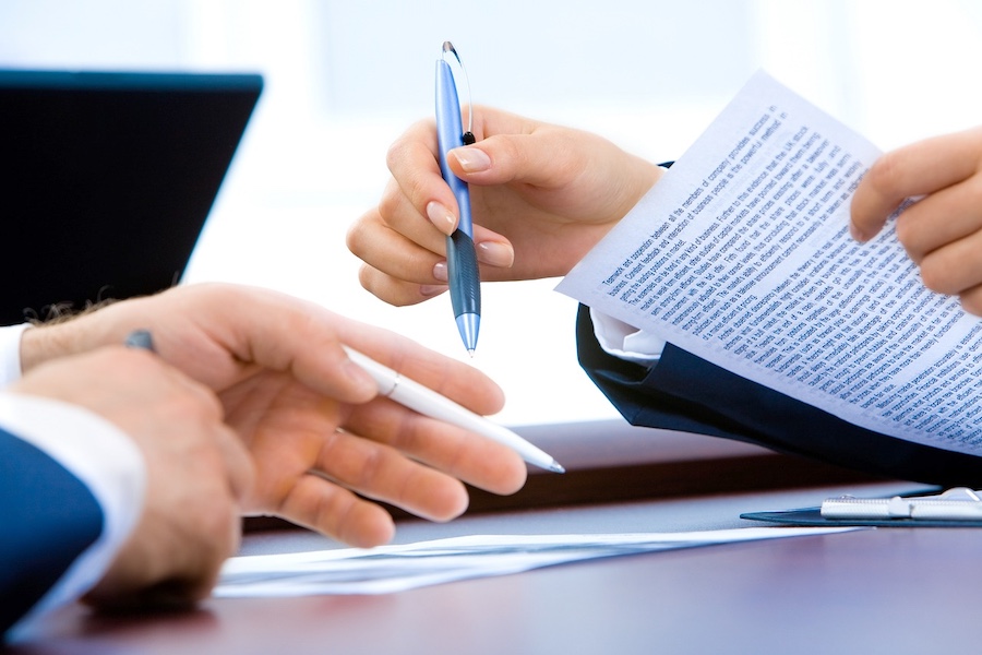 Closeup of two hands going over business paperwork at a table.