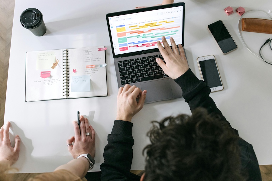 Coworkers looking at a planning calendar on a laptop.