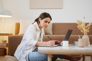Woman sitting in living room working on a resume refresh.