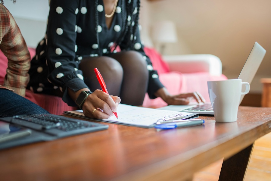 A woman using a red pen to edit application materials.