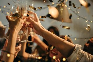 Hands in the air toasting the New Year with metallic confetti swirling.