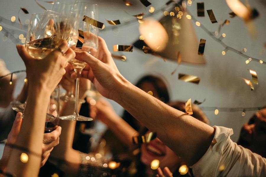 Hands in the air toasting the New Year with metallic confetti swirling.