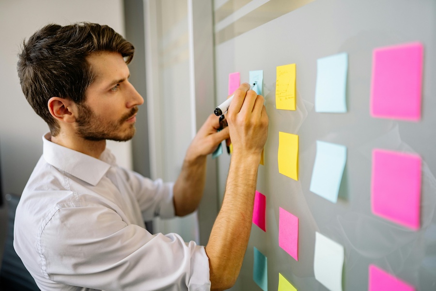 Manager putting notes on a board as he plans for his team's future.