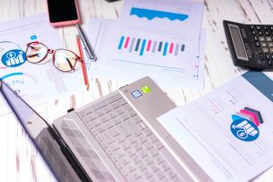 A work surface with printouts, glasses, a laptop, and more.