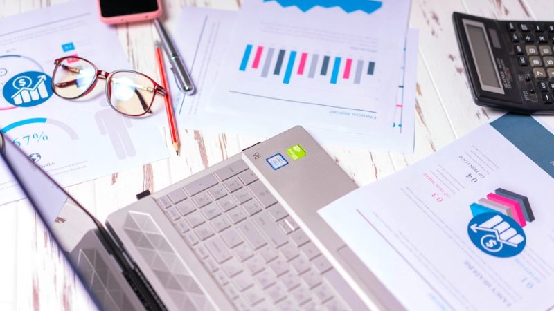 A work surface with printouts, glasses, a laptop, and more.