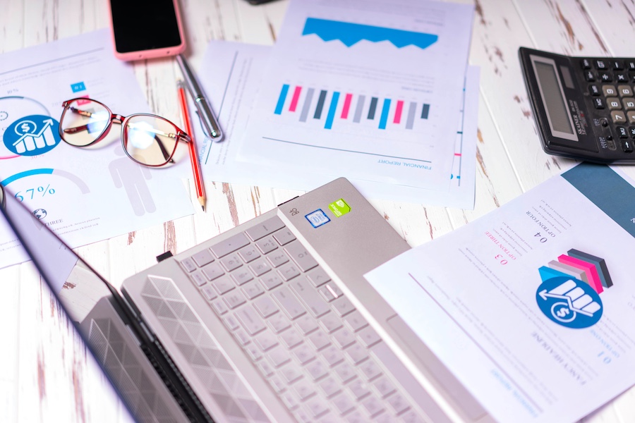 A work surface with printouts, glasses, a laptop, and more.