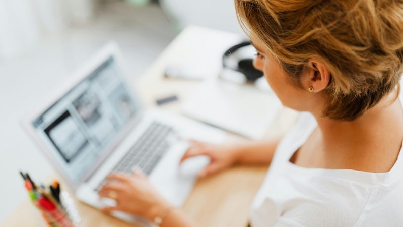 Woman looking down at a laptop screen. Information on the screen and on the tabletop is blurry.