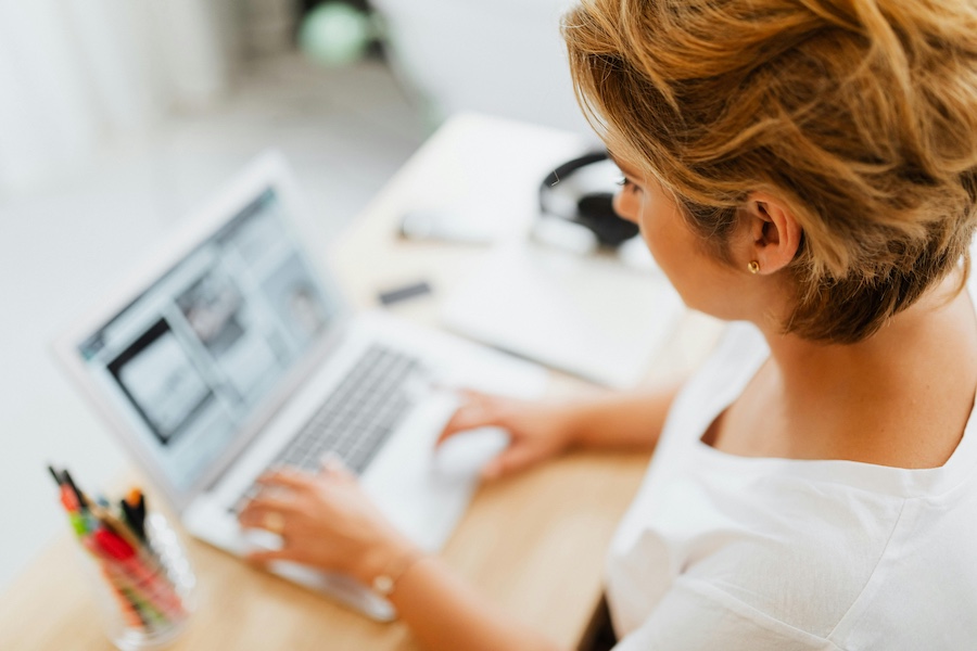 Woman looking down at a laptop screen. Information on the screen and on the tabletop is blurry.
