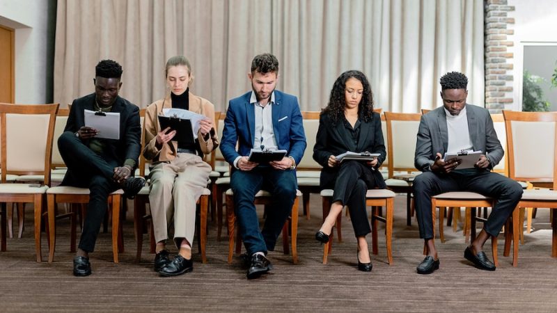 Five people sitting in a line reviewing paperwork.