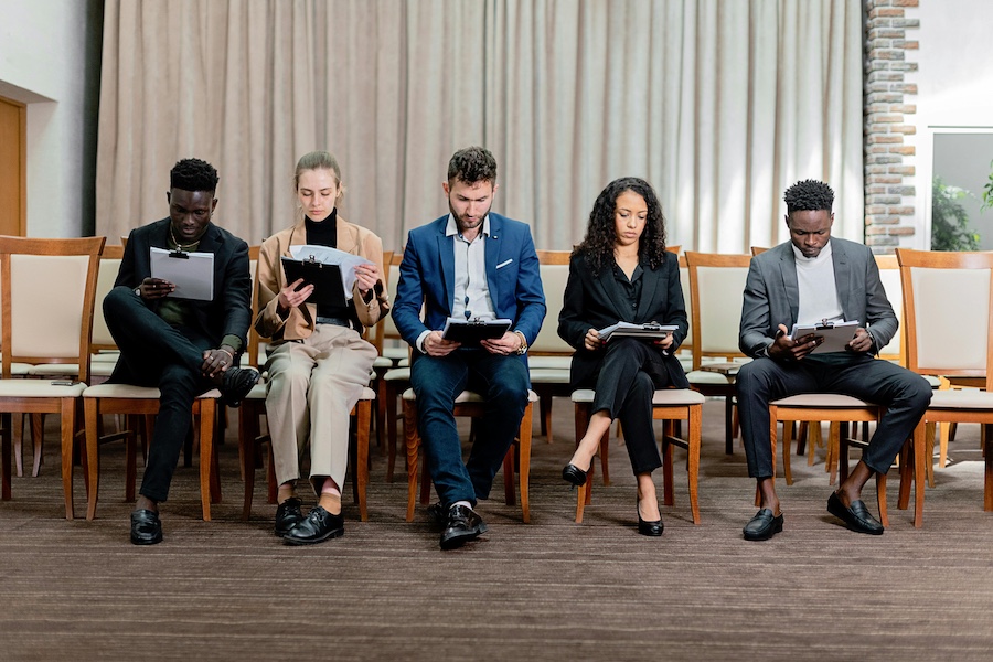 Five people sitting in a line reviewing paperwork.