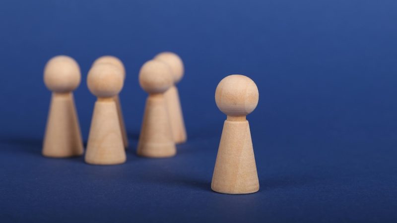 A group of wood pieces against a blue background with one standing out from the others.