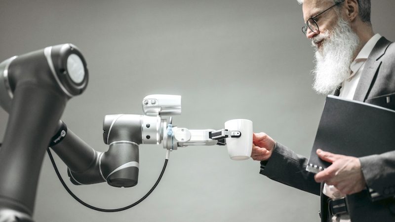 A robot handing a man a cup of coffee,