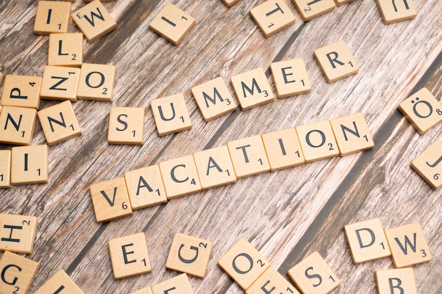 Game tiles on a wood table spelling out "summer vacation"