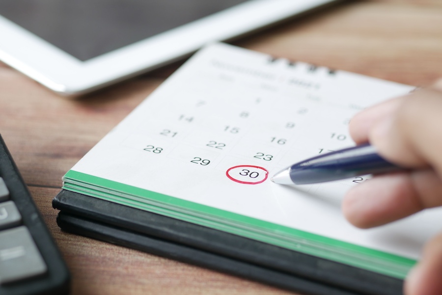 A calendar on a desktop with a person circling a date in red.